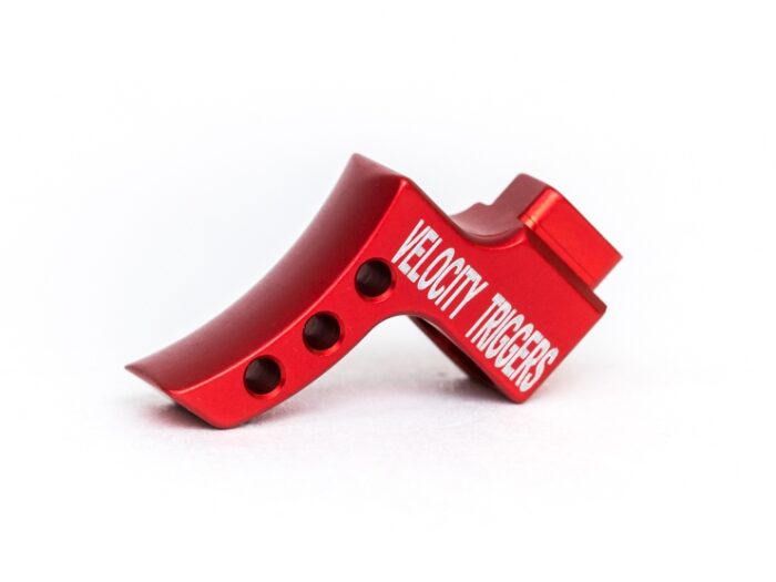 Red metal firearm trigger labeled 'Velocity Triggers' on a white background.