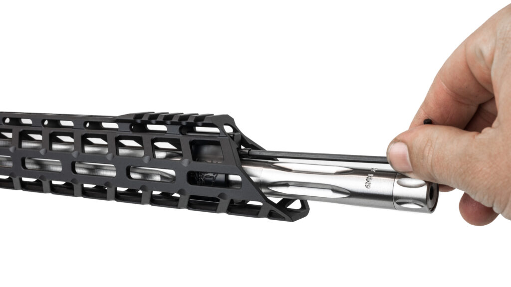 A close-up photo showing a hand using a long Allen wrench to adjust an adjustable gas block underneath the handguard of an AR-15 rifle with a stainless steel, fluted 6mm ARC barrel.