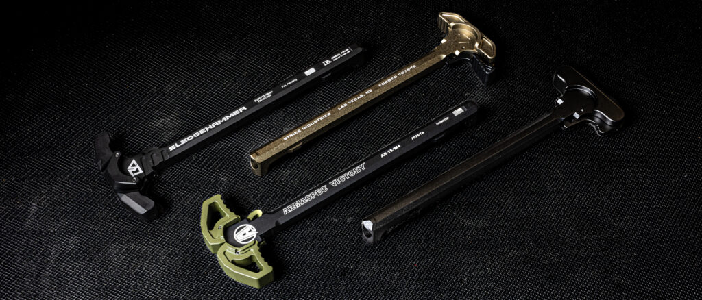 A premium lineup of modern sporting rifle charging handles is displayed on a textured black backdrop. The image captures various latch designs, anodized color finishes including black, OD green, and FDE, and clear brand laser engravings from industry-leading manufacturers including Breek Arms, Strike Industries, and Armaspec.